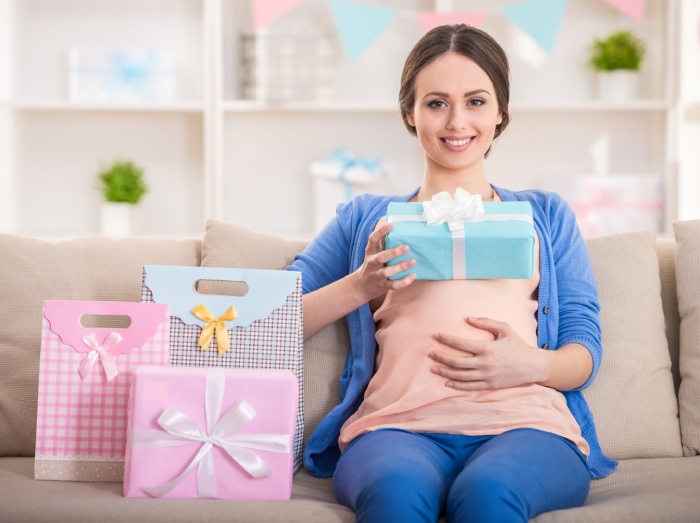 Pregnant woman sitting with baby shower gifts