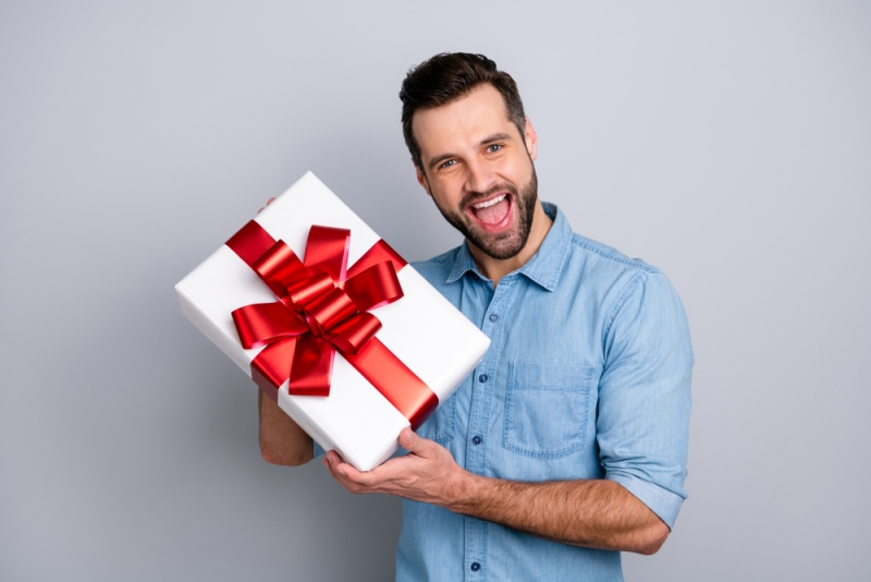 Smiling man opening a Christmas gift