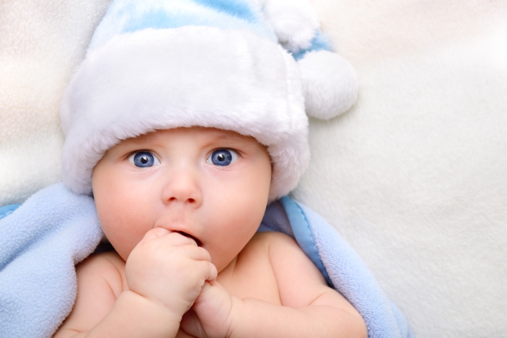 Baby boy in blue Santa hat looking at camera