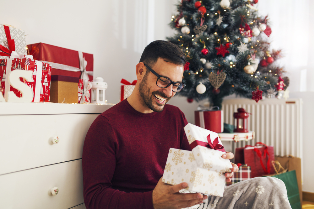 Smiling man opening a Christmas gift