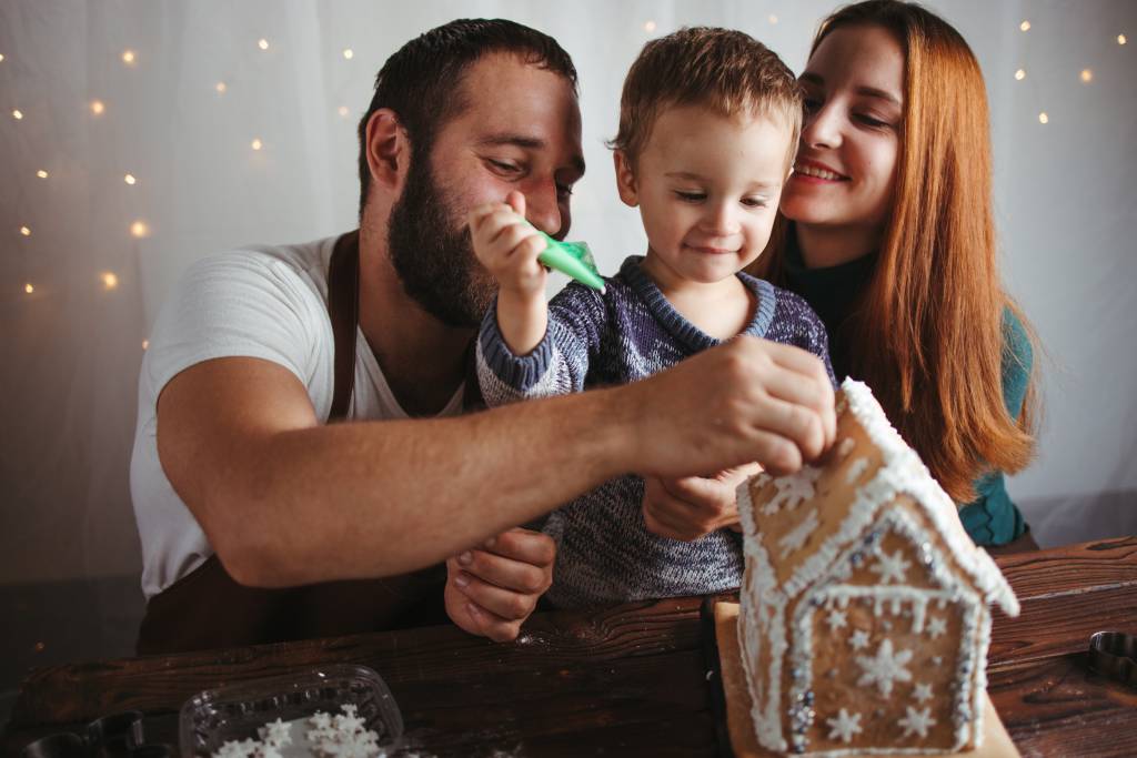 Young family making a gingerbread house together